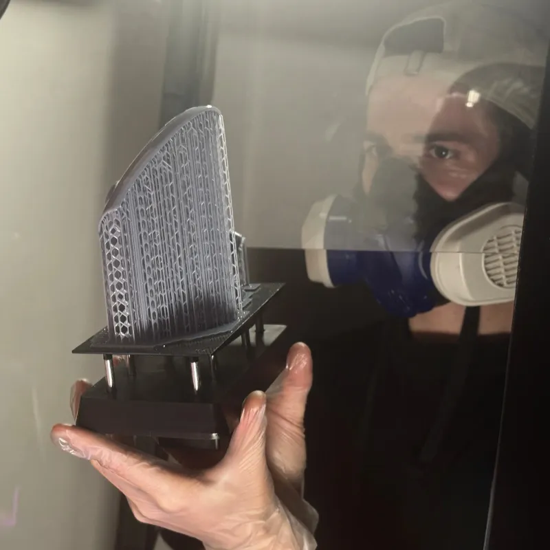 Sortie d'une pièce imprimée en résine, encore sur son plateau et ses supports, à la sortie de l'imprimante SLA de l'atelier SCULPTA