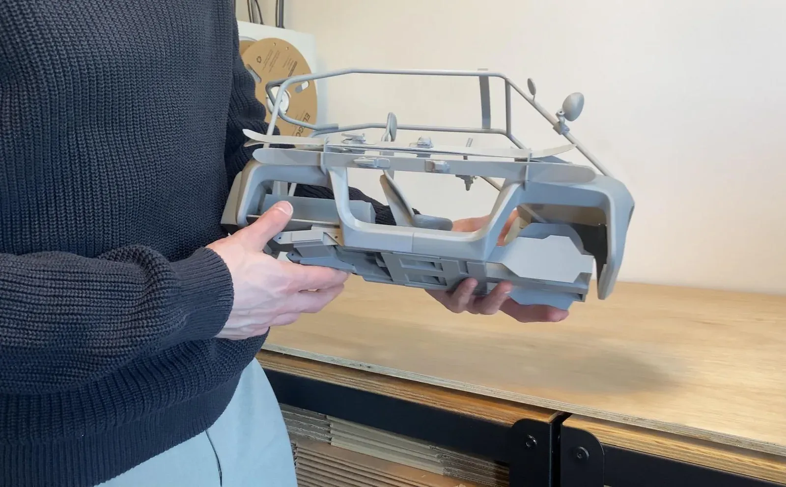 Maquette de véhicule grise imprimée en FDM, tenue en main à l'atelier